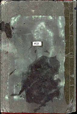 Cover of sketchbook 12A: worn grey-green board mottled with dark stains, taped spine, and a tiny white '#12' label at center