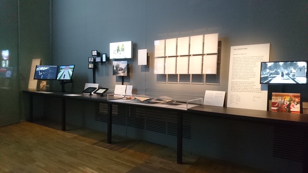 Tale of Tales's The Graveyard installed in the V&A Videogames exhibition: monitors, notebooks, and framed sheets along a dark gallery wall Tale of Tales's The Graveyard installed in the V&A Videogames exhibition: monitors, notebooks, and framed sheets along a dark gallery wall