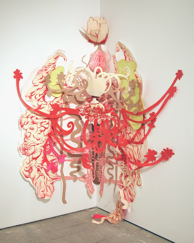 Gallery corner installation of cut paper: red arteries, cream intestines, and green organs cascading down the white walls onto the concrete floor